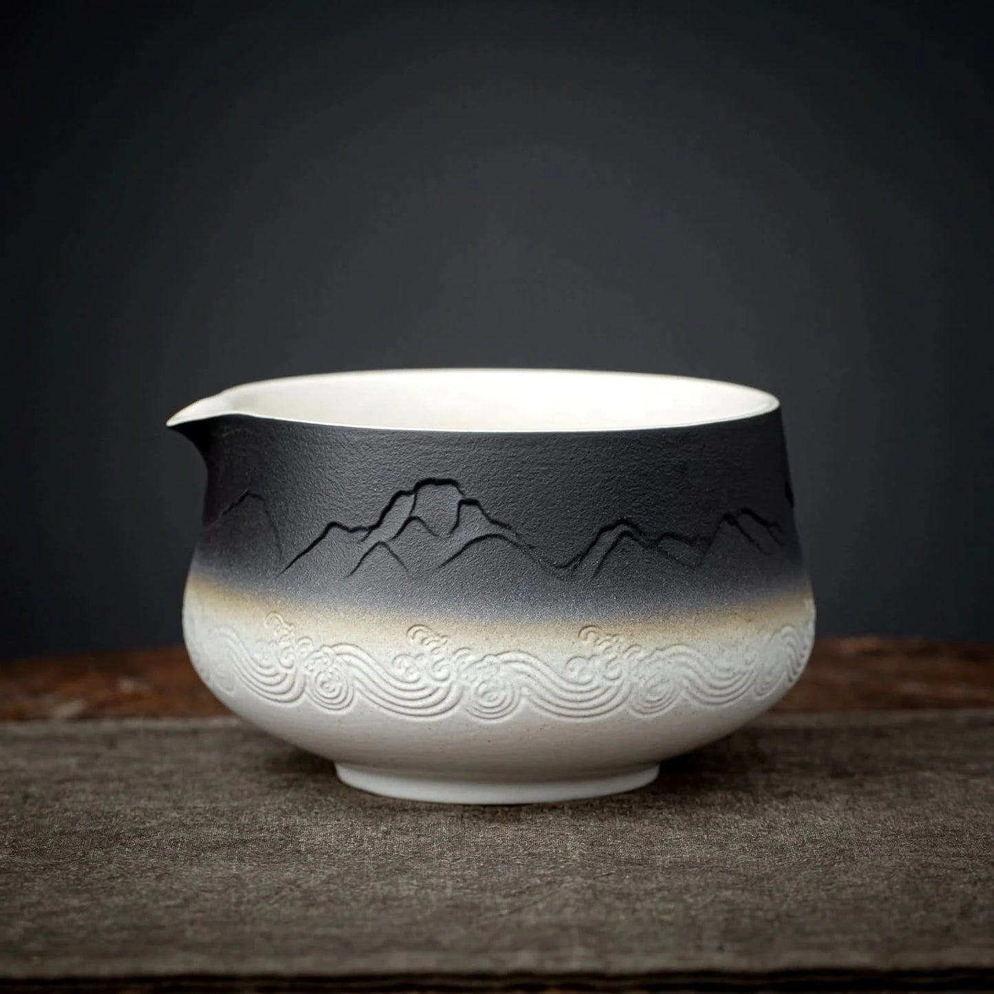 Ceramic bowl with mountain and wave designs on a dark background