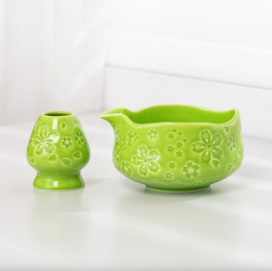 Green ceramic pitcher with floral patterns on a white background