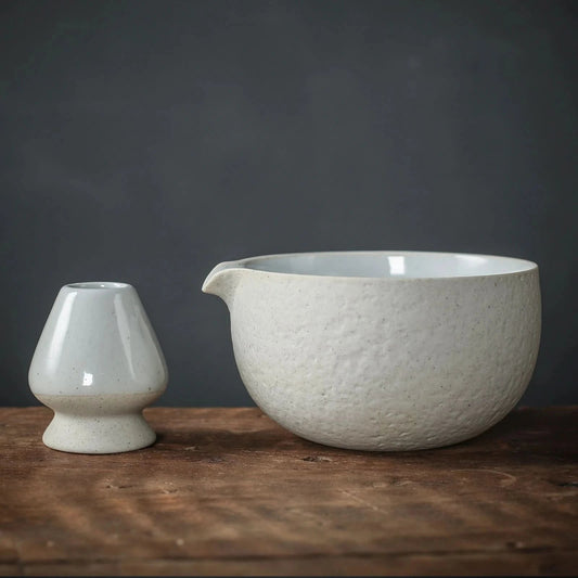 Two ceramic pieces on a wooden surface with a dark background