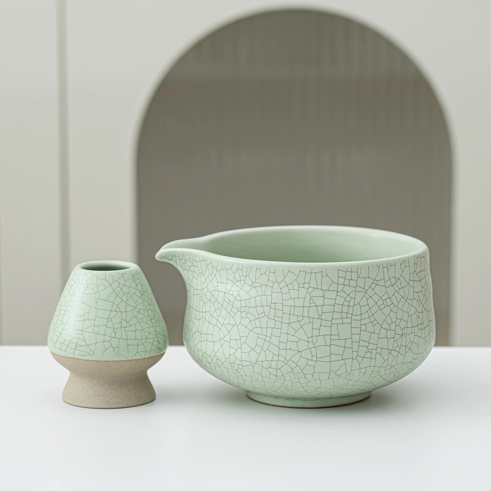 Two green ceramic vases with a cracked glaze pattern on a white surface.