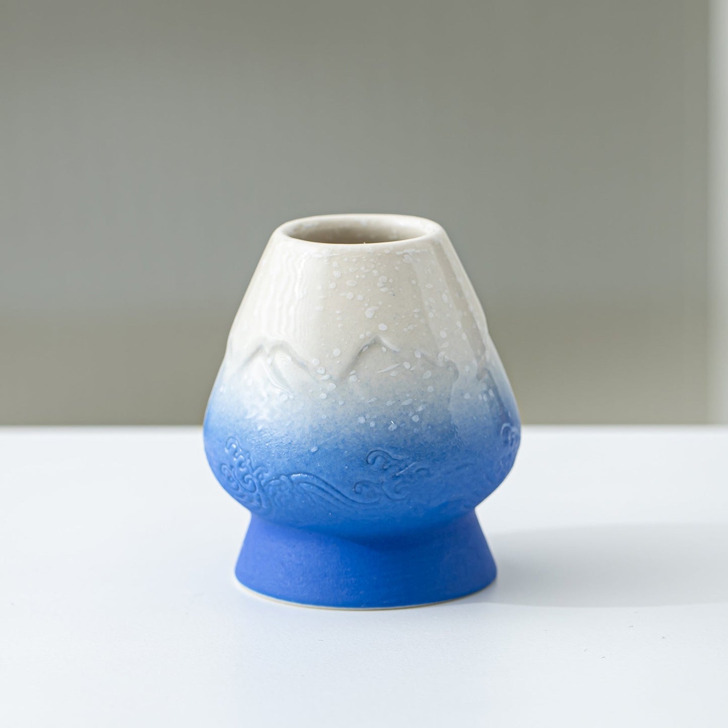 Ceramic vase with gradient from white to blue on a plain background