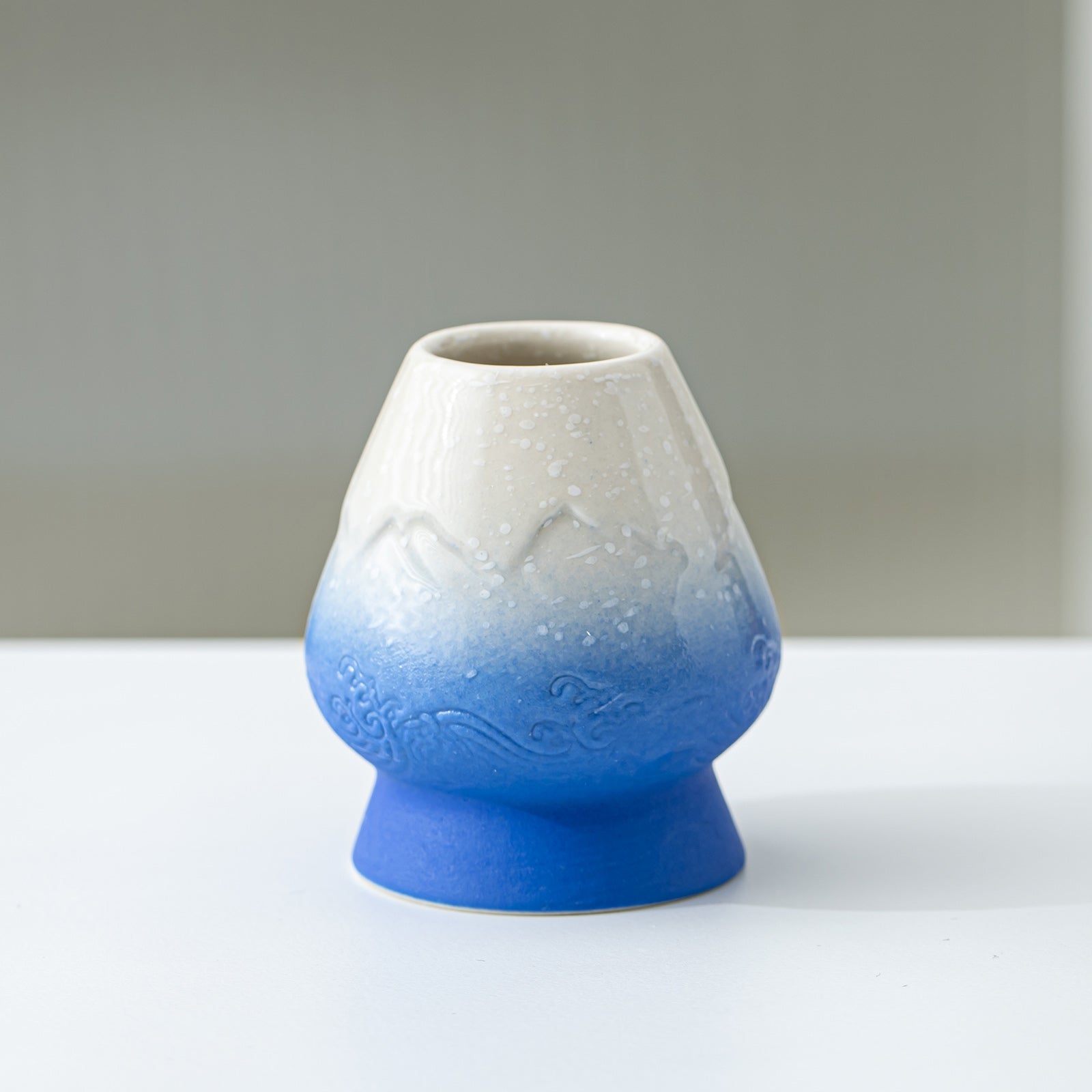 Ceramic vase with gradient from white to blue on a plain background