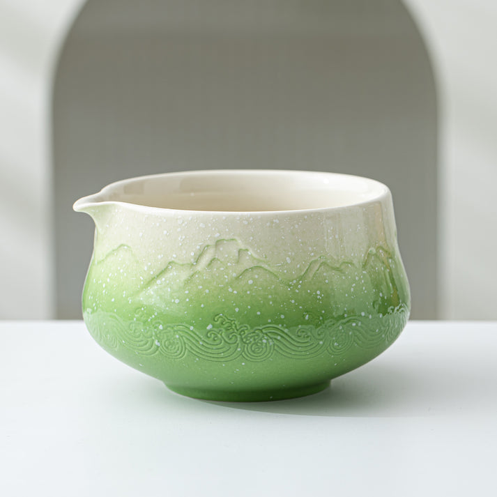Ceramic pitcher with green and white design on a white surface